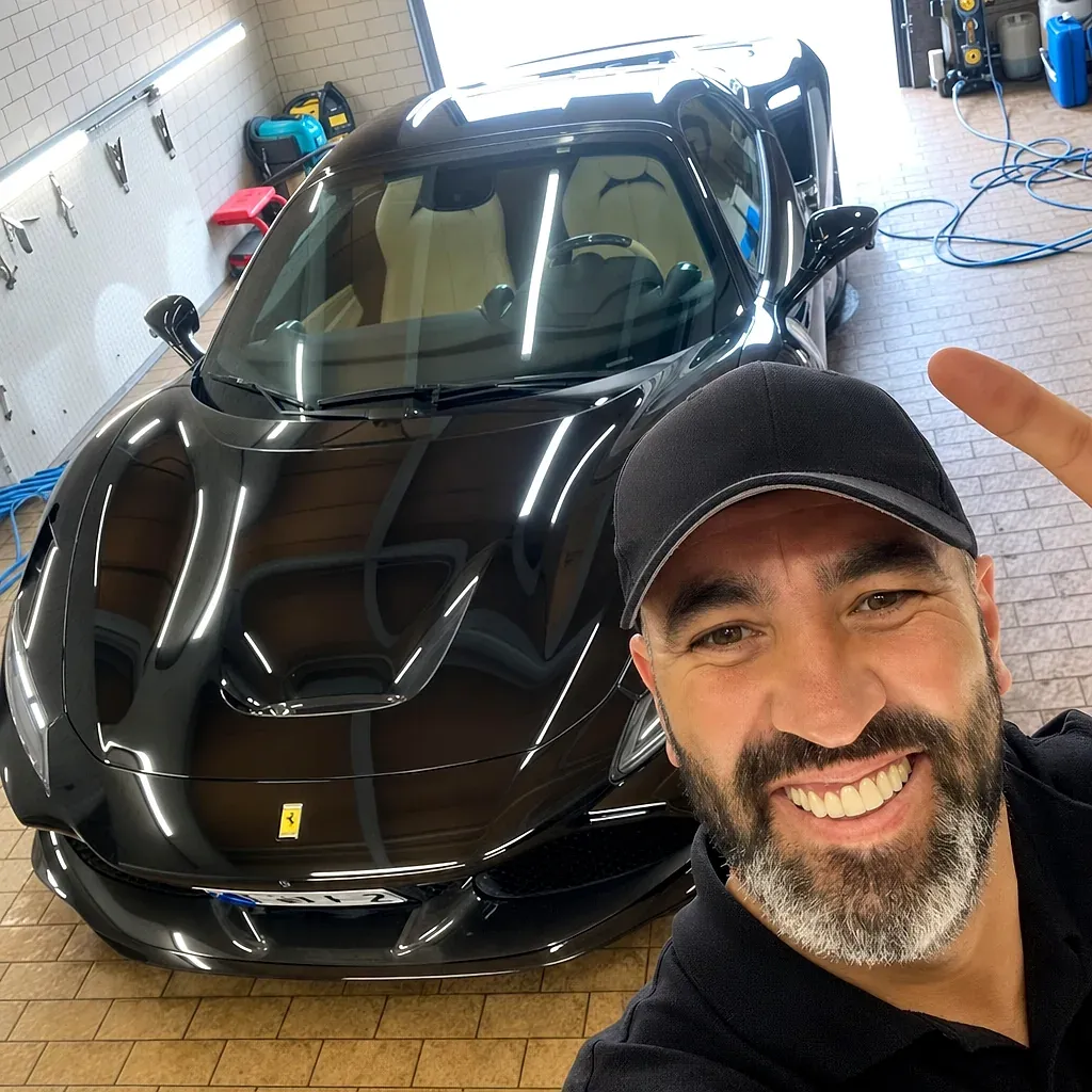 Inhaber Mimon Zaim mit frisch aufbereitetem schwarzem Ferrari bei Car Cleaner Dietzenbach