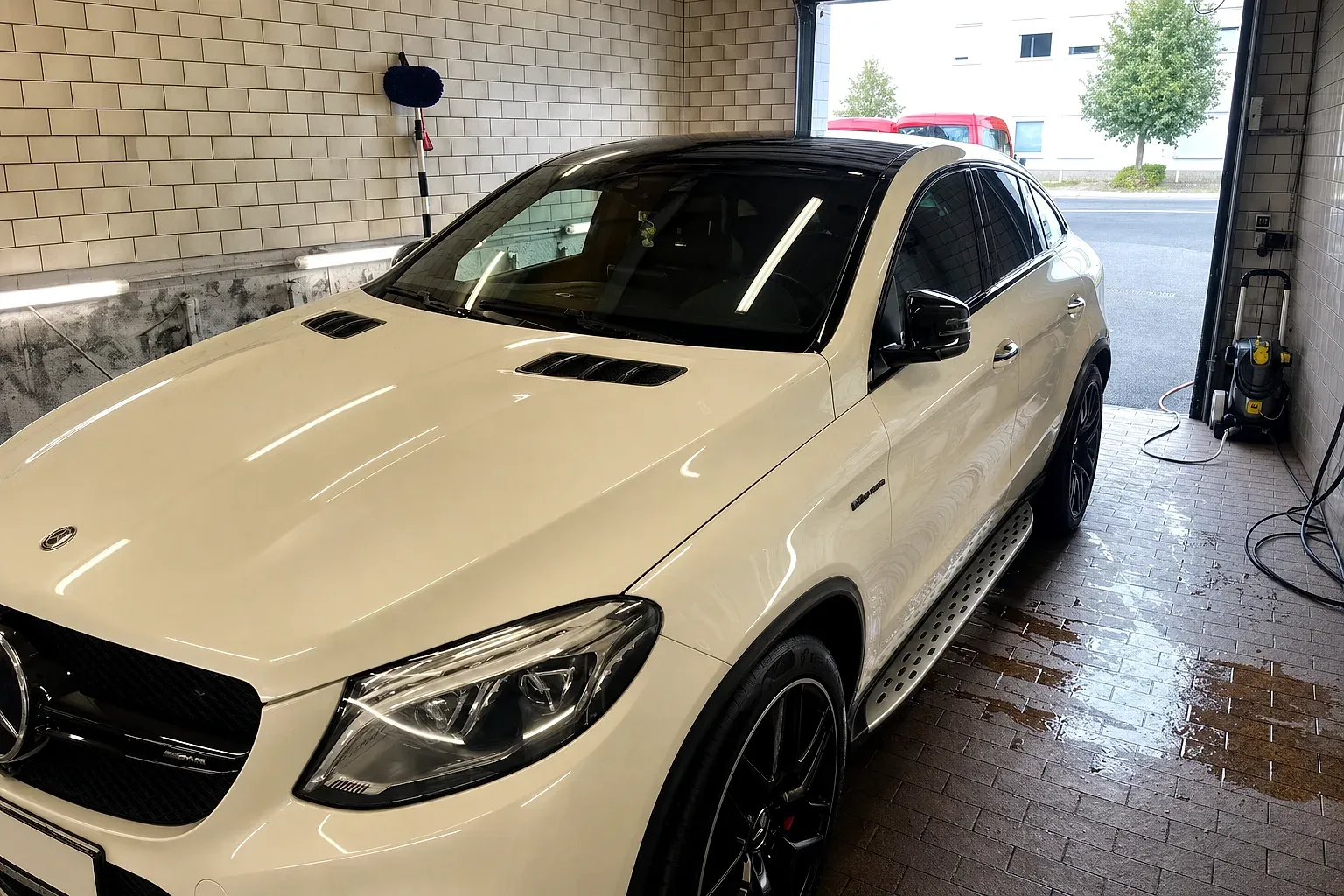 Weißes Mercedes-AMG GLE Coupé am Tor der Aufbereitungshalle
